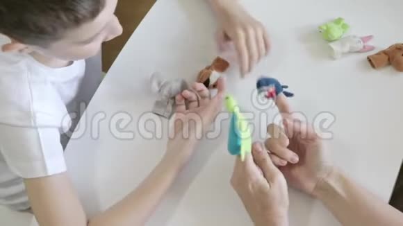 一个白种人的男孩和心理学家一起玩心理治疗师用手指木偶扮演不同的角色用玩具来表达视频的预览图