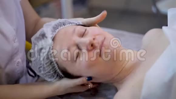 美丽年轻女性放松女性接受面部按摩美容水疗视频的预览图