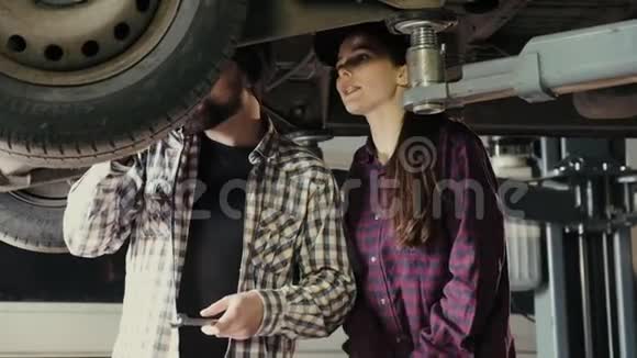 一个男人一个导师向一个女人一个服务站的新手解释汽车维修和保养的原则视频的预览图