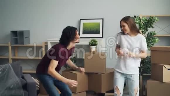 年轻男子和妇女跳舞微笑着在家中开心地庆祝搬迁视频的预览图
