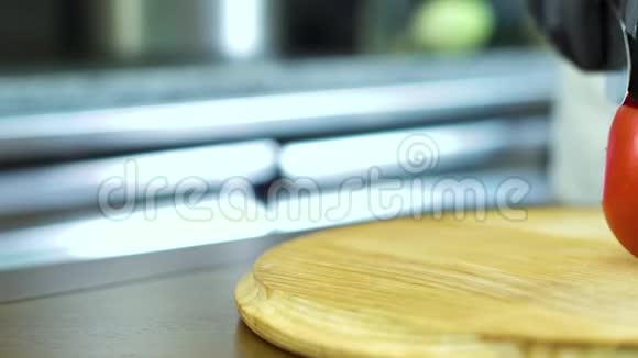 厨师手在手套上的全景特写在木切割板上切片番茄视频的预览图