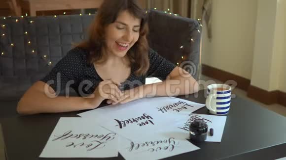一位年轻女子用刻字技巧在纸上书写书法的特写镜头她用言语看着床单视频的预览图