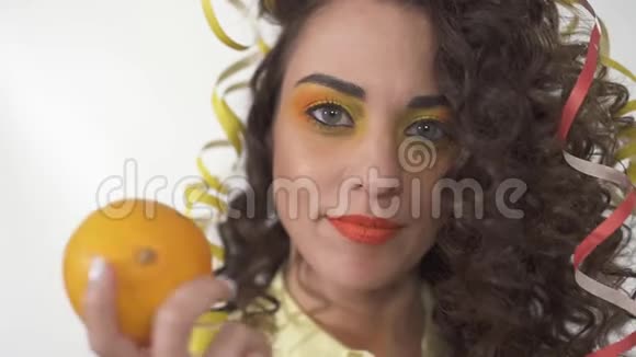 特写一幅年轻活泼的微笑女孩的肖像她用明亮的妆容捧着橙色和滑稽的母猪视频的预览图