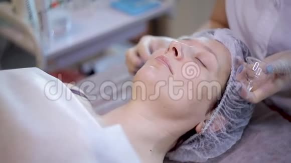 戴手套的美容师把透明的凝胶贴在年轻女人的脸上视频的预览图