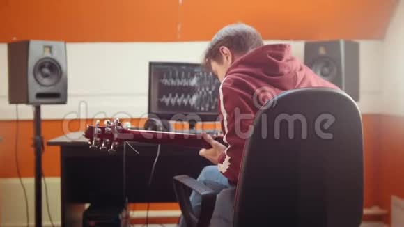 一个音乐家坐在录音室的电脑旁录制一首歌带上耳机把它戴在头上视频的预览图