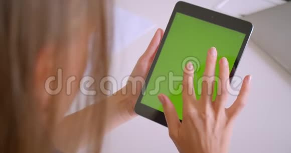 特写后景照片年轻迷人的白种人妇女使用平板电脑与绿色的关键屏幕在办公室视频的预览图