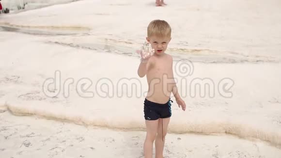 在帕穆卡莱的石灰华游泳池和露台上玩耍的小男孩的特写镜头视频的预览图