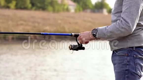 在湖边钓鱼一个人正在钓鱼那家伙把鱼从湖里拉出来鱼在钩子上视频的预览图