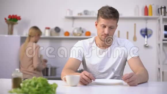 饥饿的男人急切地等待晚餐妻子在后台做饭饥饿视频的预览图