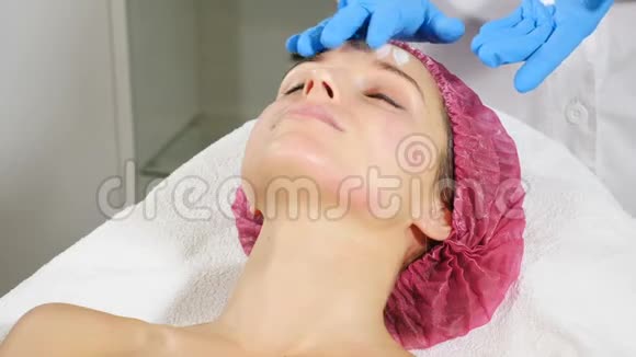 在水疗沙龙接受美容治疗的女人医用手套美容师戴美容面具皮肤护理概念视频的预览图