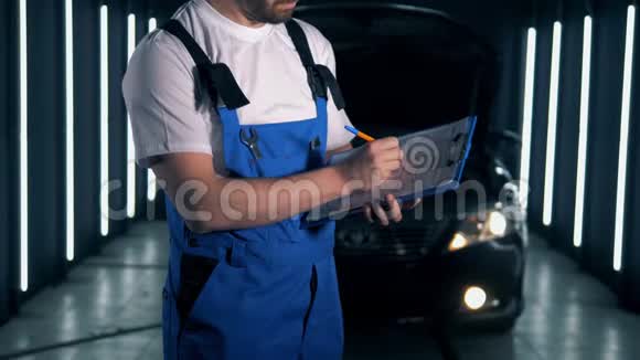 仆人站在一辆汽车旁正在夹板上做笔记汽车服务理念视频的预览图