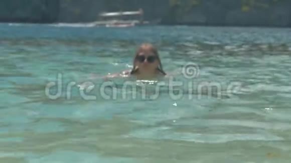 年轻漂亮的金发女孩戴着太阳镜在海里游泳的肖像度假胜地的快乐女人蓝色的海洋和幸福的女人视频的预览图