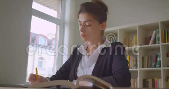 年轻漂亮的高加索女学生在大学图书馆做笔记的特写镜头视频的预览图