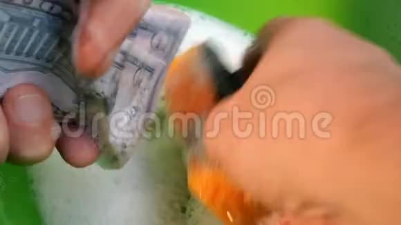 人类用海绵洗手用肥皂泡沫包装美元洗钱的概念视频的预览图