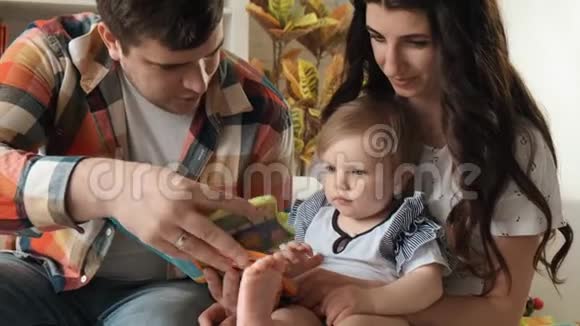 快乐的父母拥抱她的宝贝女儿玩耍在家里玩得开心慢动作视频的预览图