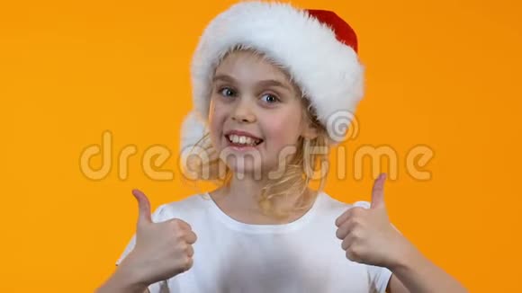 戴着圣诞老人帽子的可爱小女孩竖起大拇指对着镜头微笑视频的预览图