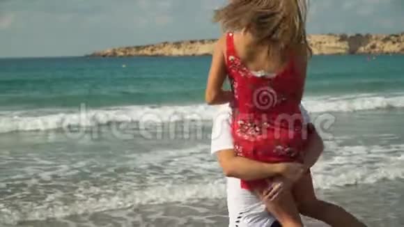 长胡子的男人把穿着衣服的女孩抱起来在海滩上和她一起旋转快乐的一对夫妻视频的预览图