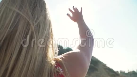 金发女孩向太阳伸出手年轻女子用手指玩阳光可爱的女孩把时间花在视频的预览图