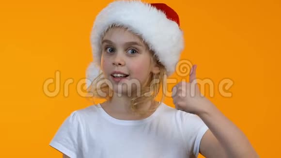戴着圣诞帽的小女孩子在镜头前竖起大拇指和眨眼度假视频的预览图