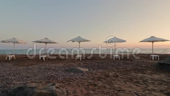 在海滩上夕阳西下一排排沙滩阳伞在微风中轻轻地吹着视频的预览图