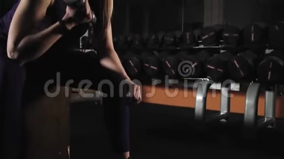 年轻的体育女孩晚上在健身房订婚锻炼举哑铃坐视频的预览图
