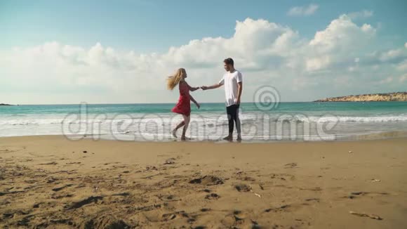 年轻的小伙子和漂亮的女孩穿着漂亮的夏装在海边跳舞轻轻地拥抱慢动作视频的预览图