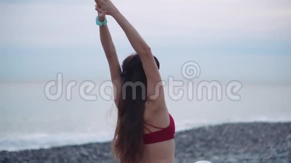 女运动员正在暖身在阴天打坐在海边视频的预览图