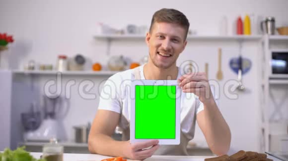 帅哥拿着绿色屏幕的平板电脑烹饪课程申请视频的预览图
