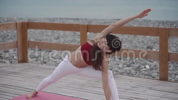 女瑜伽师在海边的海滩上锻炼身体视频的预览图