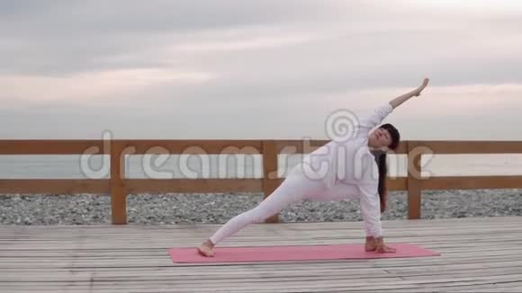 强壮的女人正在做瑜伽姿势双手靠在地板上海岸在后面视频的预览图