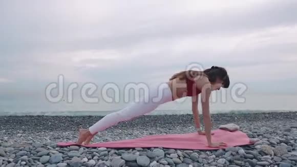 早上女人在海滩上表演木板姿势靠近大海视频的预览图