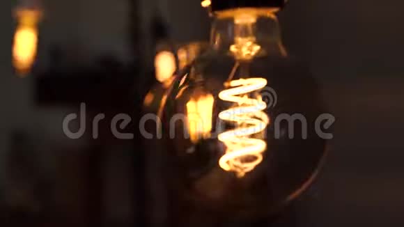 几个黄色明亮的老式灯泡在黑色背景中摆动光和暗的概念思想电视频的预览图