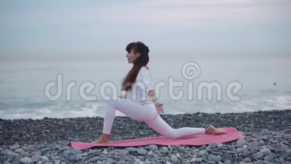 女运动员白天在鹅卵石海岸练习瑜伽视频的预览图
