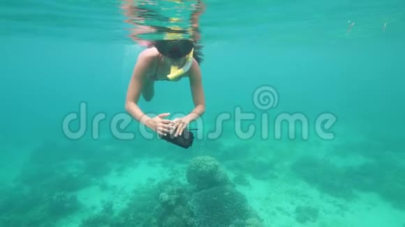 戴着浮潜面具的女人带着珊瑚在蓝色的海洋里游泳视频的预览图