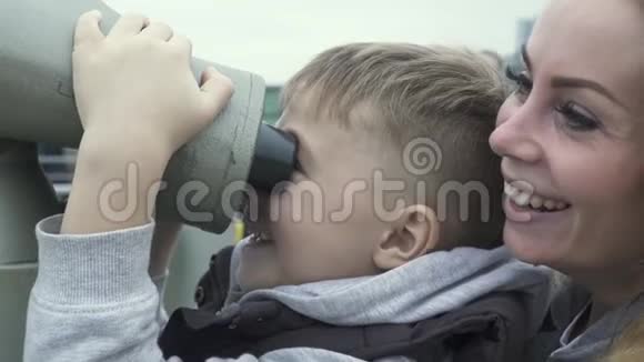 旅游男孩一起旅行时用旅游望远镜看城市全景游客看望远镜视频的预览图