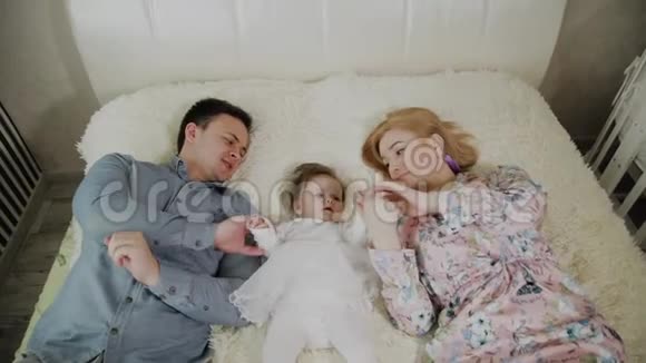 妈妈今天年轻可爱开朗的家庭在床上妈妈爸爸还有小可爱的女儿视频的预览图
