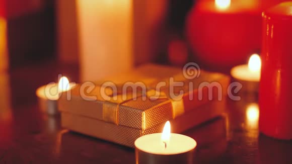 特写4k镜头的黄金礼盒和燃烧蜡烛在木桌上的夜晚完美的背景或背景视频的预览图