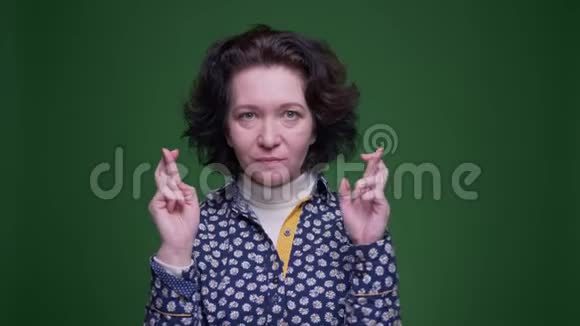 一位老白种人深色头发的女性的特写镜头她的手指交叉着焦虑和担忧地看着镜头视频的预览图