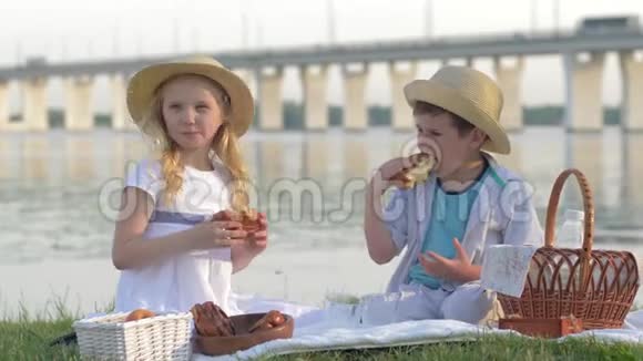 孩子们的食物饥饿的朋友戴草帽的小男孩和女孩在大自然野餐时吃甜面包喝牛奶视频的预览图