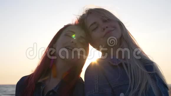 女朋友在夕阳的背景下微笑风吹拂着她们的头发阳光阳光在她们的头间闪耀视频的预览图