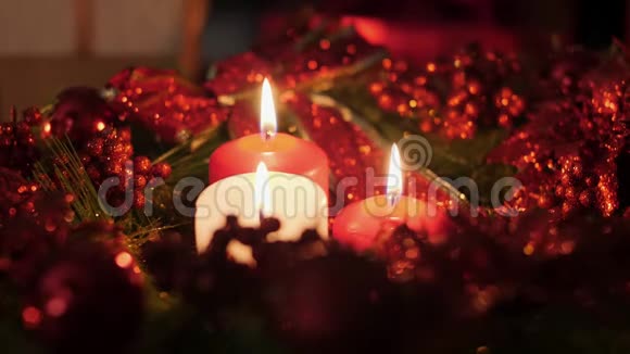 特写4k镜头三支红白蜡烛在来临的圣诞花环晚上燃烧完美的背景或视频的预览图