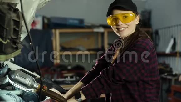 一个漂亮的黑发女孩一个汽车维修技工戴着帽子和格子衬衫修理汽车发动机和视频的预览图
