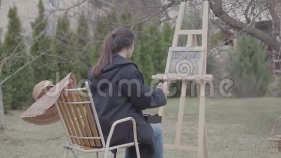 熟练的艺术家在后院的画布上画画美丽热情的女孩从事创造力启示视频的预览图