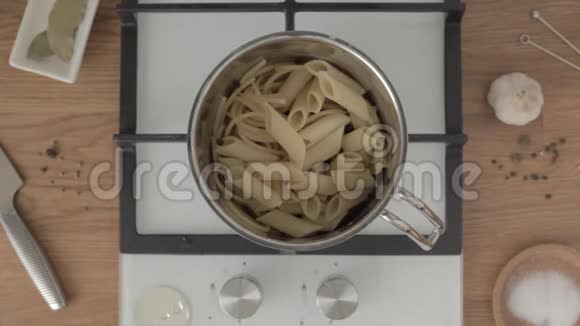 手把意大利面条和笔混合在金属锅里用勺子在厨房里视频的预览图