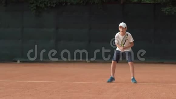 打网球坚定的运动员少年集中精力在红场上比赛和拍球视频的预览图