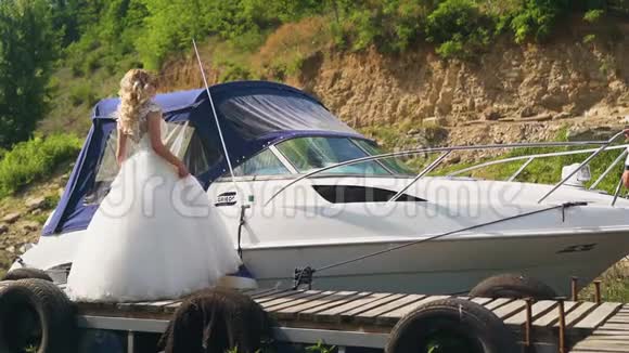美丽的新娘站着在晴天的帆船上在游艇上摆姿势慢动作视频的预览图