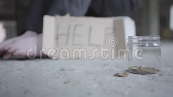 无家可归的男人或女人坐在一座废弃的建筑里拿着一个纸箱标志帮助和罐子等待资金的支持和支持视频的预览图