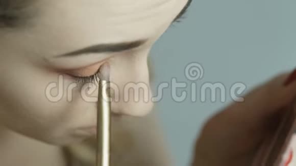 自信的年轻女人用刷子把眼影涂在眼睑上漂亮的女孩在化妆PU视频的预览图