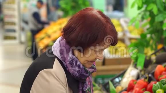 超市里一个长着皱纹的老女人抱着红萝卜视频的预览图