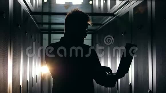 一名男技术员的剪影正在黑暗的服务室工作视频的预览图